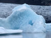 Blauer Eisberg mit Loch und Spiegelbild im Fjallsárlón